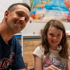 Male parent and female student smiling while sitting at a desk